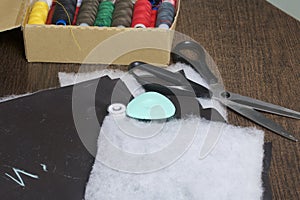 Cutting of the product for sewing. On the table is a cloth with chalk-marked garments. Nearby lie scissors, chalk and a box with c