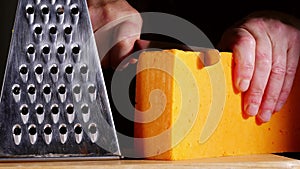 Cutting red cheddar cheese with cheese grater medium shot