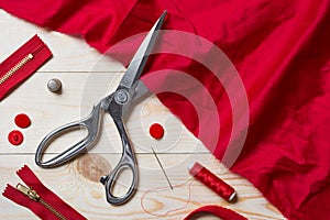 Cutting red fabric with a taylor scissors on wooden table