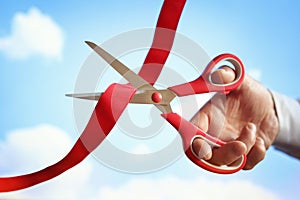 Cutting red ribbon with scissors