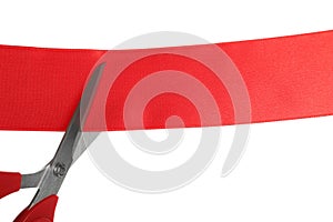 Cutting red ribbon with scissors on white background