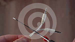 Cutting with scissors white wires of headphones with mini jack plugs close-up