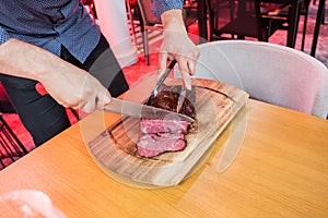 Cutting steak on wooden table