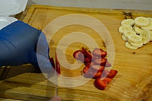 Cutting strawberries and banana on wooden table