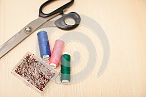 On the cutting table lie scissors, thread and pins. Work place of seamstress. topp view, place for text