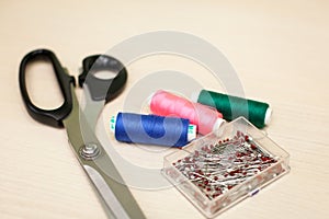 On the cutting table lie scissors, thread and pins. Work place of seamstress. topp view, place for text