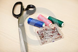 On the cutting table lie scissors, thread and pins. Work place of seamstress. topp view, place for text