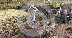 Cutting Turf Peat by spade in Moss Bog in Ireland