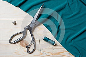 Cutting turquoise fabric with a taylor scissors on wooden table