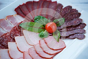 Cutting of various types of meat and sausages on a plate