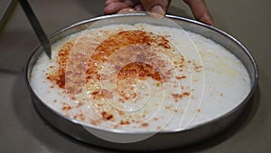 Cutting white dhokla also known as khaman in symmetrical square shape with hands  Gujrati dish made of white batter and red chilly