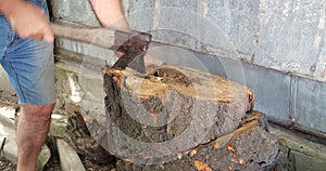 Cutting wood with a large sharp ax, Man Chops firewood, Chopping of wood on a wooden log in summer at the home