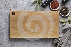 Cutting wooden board with spices and ingredients for cooking and marinade on grey. Space for text or recipe. View from above