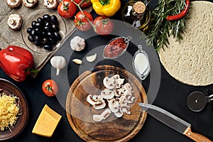 Cutting wooden board with traditional pizza preparation ingredients: cheese, tomatoes sauce, mushrooms, olive oil