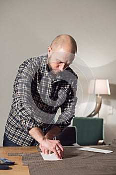 Cutting wool fabric. the line pattern. Bow ties of woolen fabric. Young man working as a tailor and using a sewing