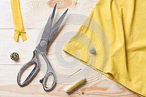 Cutting yellow fabric with a taylor scissors on wooden table