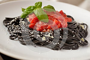 Cuttlefish ink spaghetti under tomato sauce photo