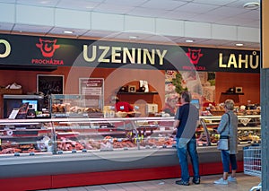 Cvikov, CZECH REPUBLIC - MAY 24, 2019: Frontal view of butcher shop in penny market with female butcher showing meat to
