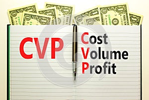 CVP cost volume profit symbol. Concept words CVP cost volume profit on white note on beautiful background from dollar bills. Pen.