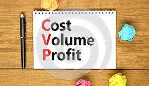 CVP cost volume profit symbol. Concept words CVP cost volume profit on white note on beautiful wooden table wooden background. Pen