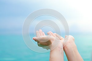 CWoman hands place together like praying from nature in front of sunset beach