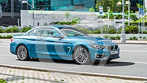 Cyan BMW 420D convertible F33 on the road in motion. Fast speed drive on city road. Front side view BMW 4 series