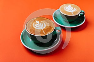 Cyan coffee cups over orange background.