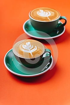 Cyan coffee cups over orange background.