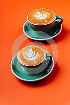 Cyan coffee cups over orange background.