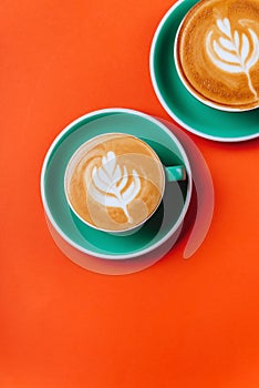 Cyan coffee cups over orange background.