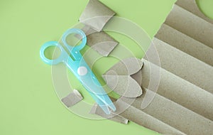 Cyan Plastic children safety scissors on table with brown paper in different shape