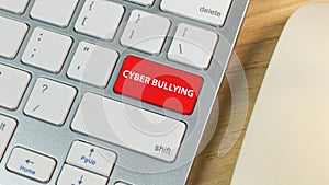 Cyber bullying red button on silver keyboard