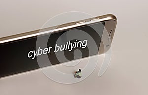 `cyber bullying` Text on Smart Phone Screen. A sitting miniature woman and a Smart phone.