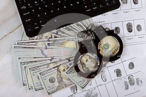 Cyber crime legal law police handcuffs on a hundred dollar bills with computer keyboard technology of fingerprint on paper