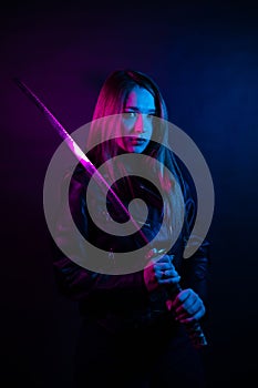 Cyber girl in a black leather jacket at dusk holds a katana. A woman in a club with a colored pink-blue light holds an Asian sword