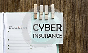 Cyber Insurance notes paper and a clothes pegs on wooden background