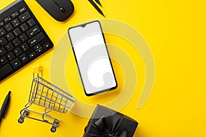 Cyber monday concept. Top view photo of mobile phone keyboard computer mouse shopping cart pencils and giftbox with ribbon bow on