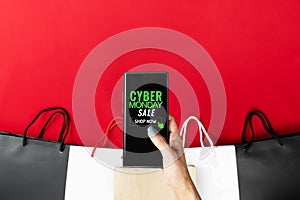 Cyber Monday Sale Clearance Discount Concept, woman hand holding smartphone with shopping bag