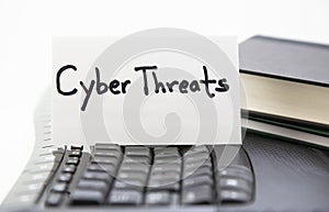 Cyber Threats lettered on card placed on computer keyboard photo