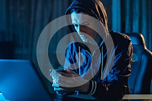 Cybercriminal hacker in the hood typing program code while stealing access databases with passwords. Cyber security