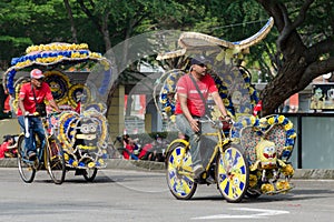 Tourist entertainment - trishaw on his customized tricycle transport, brightly decorated with children`s cartoon and flowers.