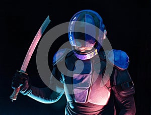 Cyberpunk future concept. Bionic cyborg police officer with short samurai sword stands in dark. Halfman robot looks at camera. photo