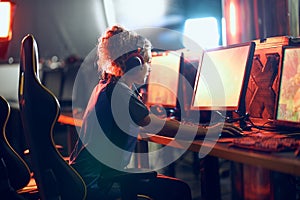 Cybersport concept. Side view of a focused teenage girl, professional gamer wearing headphones participating in eSport