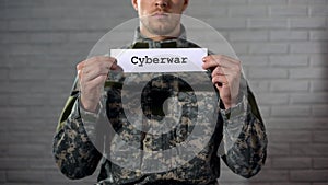 Cyberwar word written on sign in hands of male soldier, information security