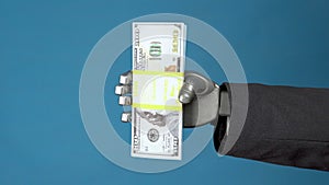 Cyborg businessman in a suit holds a pack of dollars. A mechanical hand shows a bundle of money on a blue background.