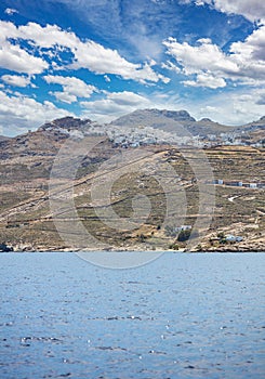 Cyclades Greece. Serifos island Chora town white building uphill on rocky land, rippled Sea