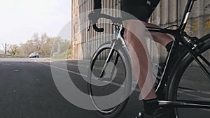 Cycling concept. Strong leg muscles pedaling bicycle. Cyclist riding bike out of the saddle. Close up follow shot.