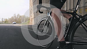 Cycling concept. Strong leg muscles pedaling bicycle. Cyclist riding bike out of the saddle. Close up follow shot. Slow motion