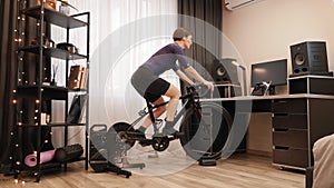 Cycling on exercise bike. Woman is training on smart indoor stationary bicycle. Female is riding on cycling trainer and doing fitn