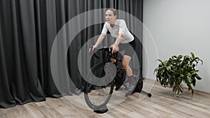 Cycling indoors on smart trainer preparing for race doing hard pedaling cardio workout on stationary bike. Cycling concept.